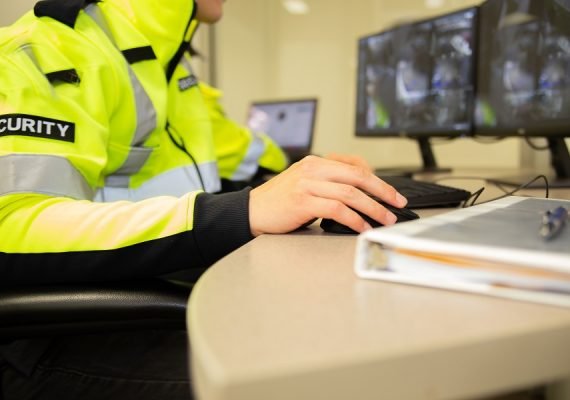 A security team watching over CCTV surveillance monitors with green screen.